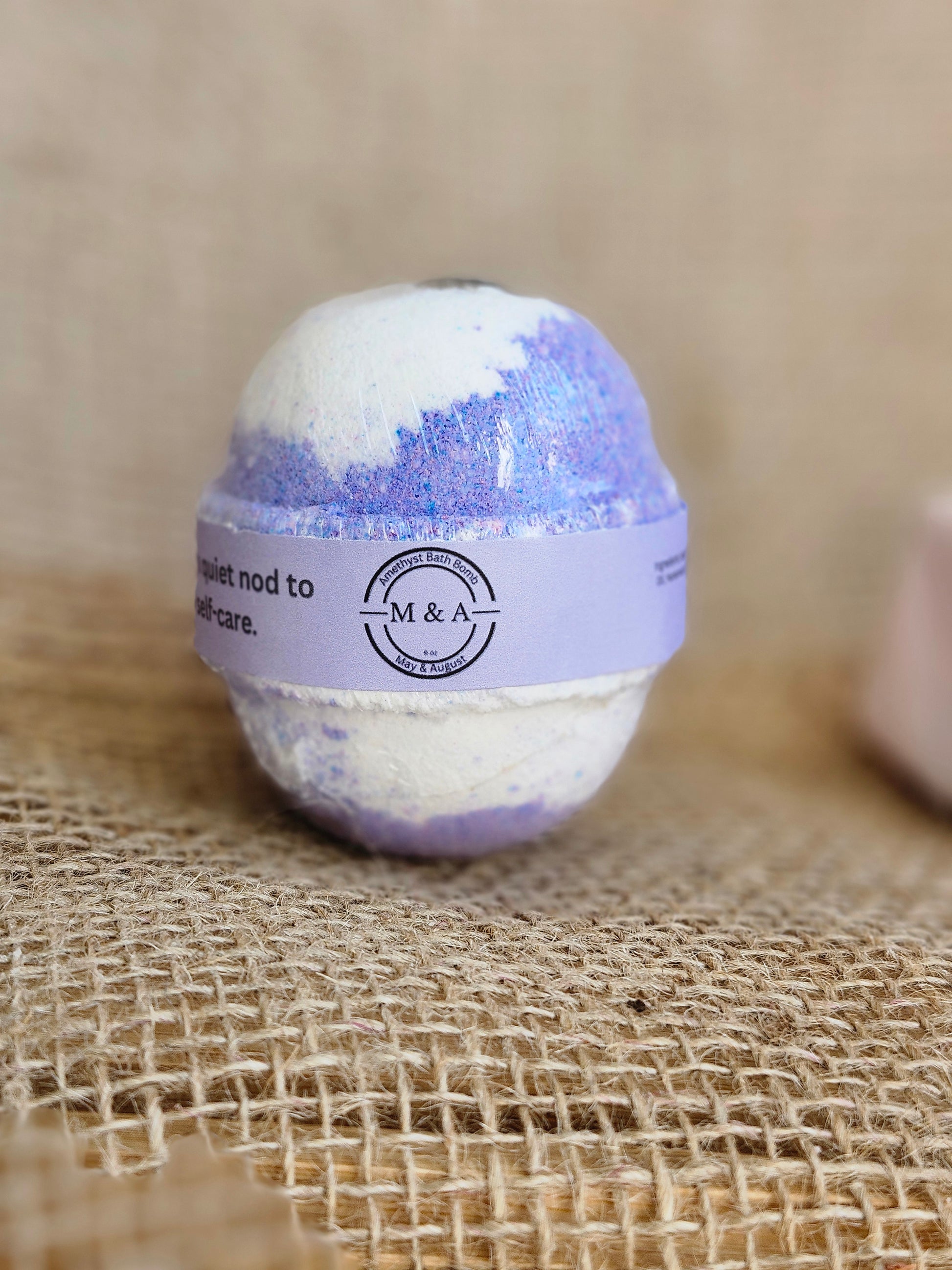Bath bomb with a purple label on a textured fabric background